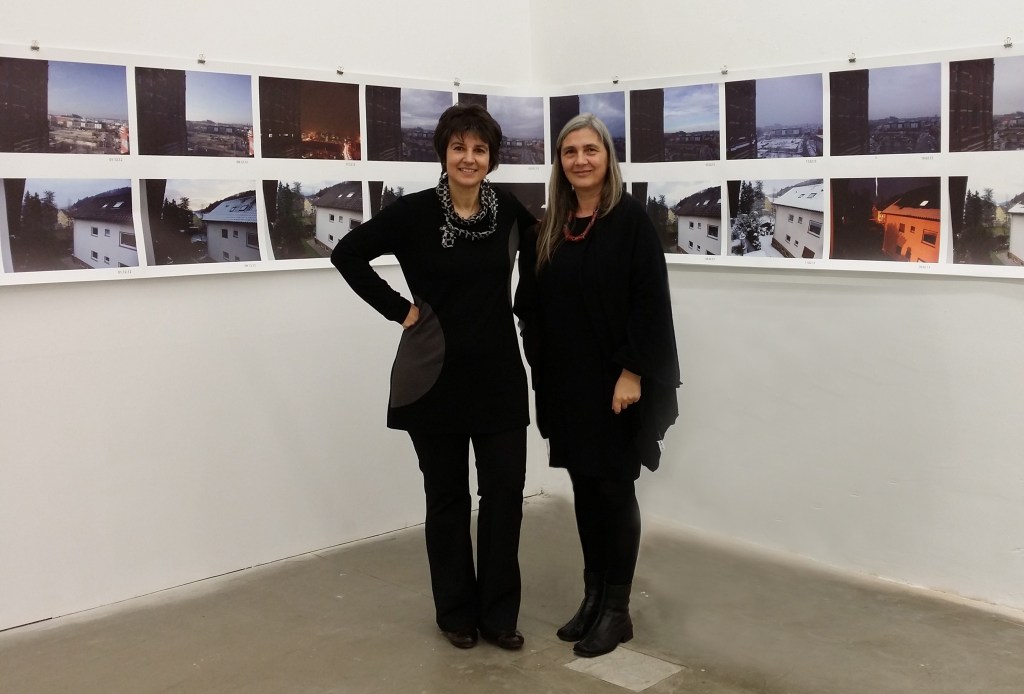 Zum Projekt „achtundvierzig“

Das Kunstprojekt „achtundvierzig“ ist ein vielschichtiges Projekt. Die Künstlerinnen Ria Hochmann aus Freiburg und Monika Rienössl aus Wien beziehen dabei das traditionelle „Fensterbild“ mit fotografischen Mitteln ebenso mit ein, wie auch Aspekte der „Land-Art“ und „Konzept-Art“.

Das Fensterbild, das schon einem eigenen Genre zugerechnet werden muss, hat seit der Romantik durch Künstler wie Caspar David Friedrich, später im 19. und 20. Jahrhundert durch Henri Matisse, Hans Purrmann, René Magritte, Robert Delaunay und andere hohe Bedeutung als Sinnbild von innen und außen, Verbildlichung der Verbindung des Menschen und seiner Gefühle mit der Außenwelt erlangt. Dabei findet sich der Betrachter des Bildes in der Rolle desjenigen, der aus dem Fenster schaut, den Blick ins Freie wahrnehmend. Bild und Fenster werden deckungsgleich. 

Bei den Künstlerinnen Ria Hochmann und Monika Rienössl wird das Fensterbild, das jeweils aus Ihren Wohnungen und ihrer Privatheit heraus aufgenommen wurde, auch zur Öffnung der gedanklichen Verbindung zur jeweils anderen Künstlerin in Richtung des 48. Breitengrads. Dabei bieten die Aufnahmen keine pittoresken Ansichten, sondern beschränken sich auf die Alltäglichkeit eines Blicks aus einem (ihrem) Fenster und weisen damit auch über das Bild hinaus auf den eigentlichen Kern der künstlerischen Arbeit hin. Dieser besteht eben im gedanklichen Zusammenhang des Kunstprojekts, das auch die Unfassbarkeit von Raum und Zeit, Nähe und Weite, privat und öffentlich thematisiert. 
Das Fensterbild, welches in der Kunstgeschichte bisher nur als Fenster nach draußen erschien, erhält in diesem Projekt nun erstmals eine Erwiderung und Erweiterung durch ein anderes gegengleiches Fenster, durch das zwar auch nach draußen geschaut wird, gleichzeitig aber spiegelbildlich zum Fenster der anderen Künstlerin. So ist jedes Fenster, aus dem heraus das Außen aufgenommen wird, Sender und Empfänger zugleich!

Einige Aspekte des Projekts sind dabei auch der „Land-Art“ zuzurechnen. Zum einen die elementare Beziehung auf den 48. Breitengrad des Erdglobus als Verbindungslinie und zentraler Punkt des Projekts, zum anderen die regelmäßigen festgelegten Zeitabschnitte, die einen Sonnenumlauf der Erde aufteilen. Ebenso steht das Kunstprojekt auch im engen Zusammenhang zur „Konzept-Art“, da sich der 48. Breitengrad selbst gar nicht darstellen lässt, sondern das gedankliche Rückgrat des Projekts bildet, um das herum die Aufnahmen und Aufzeichnungen  der Künstlerinnen stattfinden, die dann später das Geschehnis um die Idee herum konkret werden lassen und die Überlegungen der Künstlerinnen dokumentieren.

Helmut Albert, Freiburg








a c h t u n d v i e r z i g


Ein Breitengrad ist ein Teil eines gedachten Koordinatensystems auf der Erdoberfläche. Dieses ist in 360 Längengrade und 180 Breitengrade aufgeteilt. Damit kann ein Punkt an einem beliebigen Ort auf der Erde geographisch bestimmt werden. 

Ausgangspunkt für unsere Arbeit ist die Tatsache, dass sich unsere Wohnorte Freiburg und Wien auf dem 48. Breitengrad befinden. Dadurch ist die Zahl 48 zum Schlüssel unseres gemeinsamen Projekts geworden. Von unserem jeweiligen Lebensmittelpunkt aus wenden wir den Blick einander auf der „48er Linie“ zu. 
Mittels der Fotografie deuten wir den immensen Raum zwischen uns an, verbildlichen ihn. Nähe, Ferne und Vergänglichkeit werden durch bild-räumliche und zeitliche Festlegungen bestimmt. Einerseits die Distanz von 700 km, zum anderen zeitgleiche Aufnahmen in Richtung des jeweils anderen. Die Fotos zeigen die jeweilige Umgebung aus unseren Wohnhäusern heraus in Richtung einer gedachten Verbindungslinie bzw. des 48. Breitengrads.

Um eine Zeitgleichheit für das jeweilige Foto zu finden, teilten wir ein Jahr in 48 Einheiten auf. Dadurch entstand ein 8-Tages-Rhythmus. Mittels dieser Berechnung konnten wir den jeweiligen Tag für das gemeinsame Foto bestimmen. Den Blick aus dem Fenster und durch die Kamera richteten wir zueinander, das bedeutet von Freiburg nach Osten Richtung Wien und von Wien nach Westen Richtung Freiburg. Das geschah immer am gleichen Tag (Augenblick) und mit demselben Motiv. Die Idee bestand darin, aus dem Alltag heraus über ein Jahr lang kontinuierlich diese Linie aufrecht zu erhalten. 

In den Bildern werden die Stimmungen der verschiedenen Tages- und Jahreszeiten sichtbar. Kleine räumliche Veränderungen treten durch den Einjahreszeitraffer hervor. Die Verbindungslinie signalisierte unsere Verbundenheit, zeigte aber auch die Distanz. Erst bei Zusammenführen der Bilder löste sich die Distanz wieder auf, und die Verbindungslinie war wieder hergestellt.


Ria Hochmann, Freiburg und Monika Rienössl, Wien
